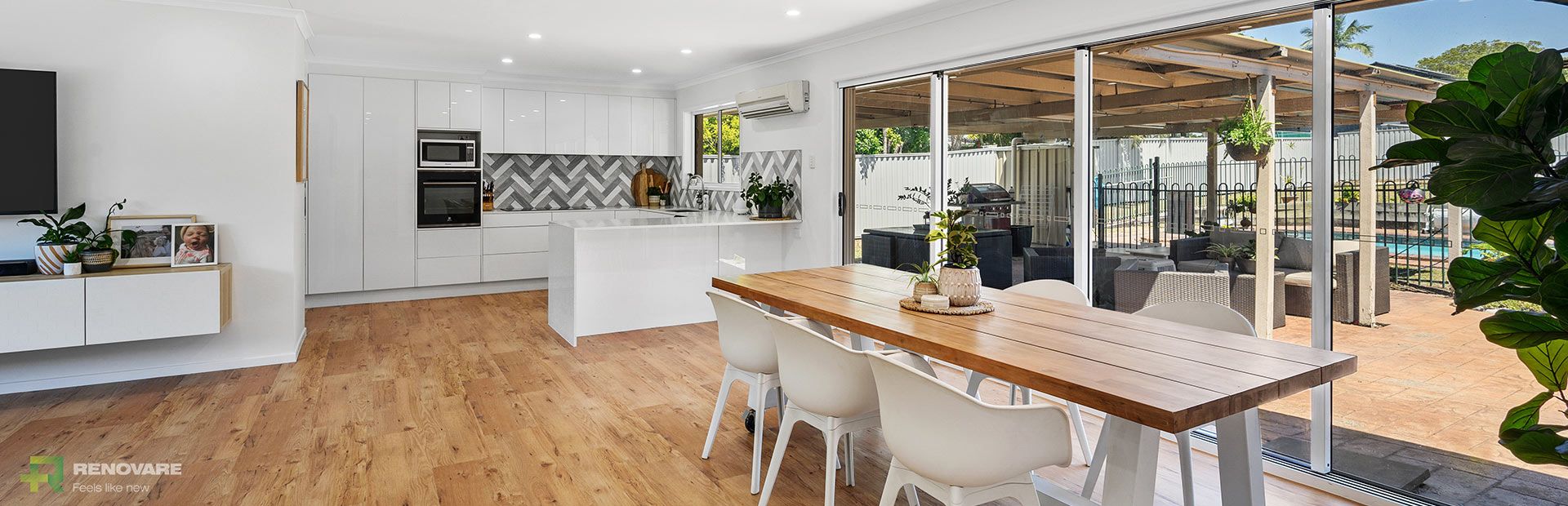 A dining table with a wooden top and a white modern kitchen. | Featured image for Brisbane Renovation Hub.