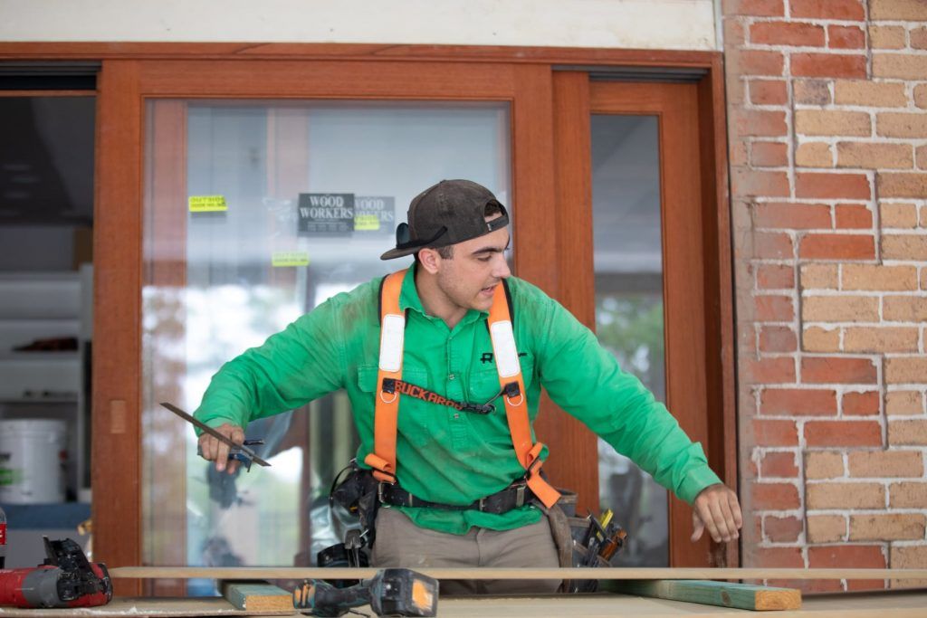 Photo of a man checking how level a board is | featured image for Granny Flat Builders.